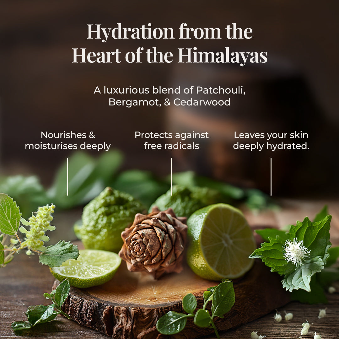 Various natural ingredients of JiViSa Aranya Glaze Buttery Body Milk are artfully arranged on a dark wooden surface, including halves of Bergamot, a Cedarwood, and Patchouli leaves. The title reads "Hydration from the Heart of the Himalayas," followed by text describing the product as A luxurious blend of Patchouli, Bergamot, & Cedarwood. Three vertical lines point to benefits: Nourishes & moisturises deeply, protects against free radicals, and leaves your skin deeply hydrated.