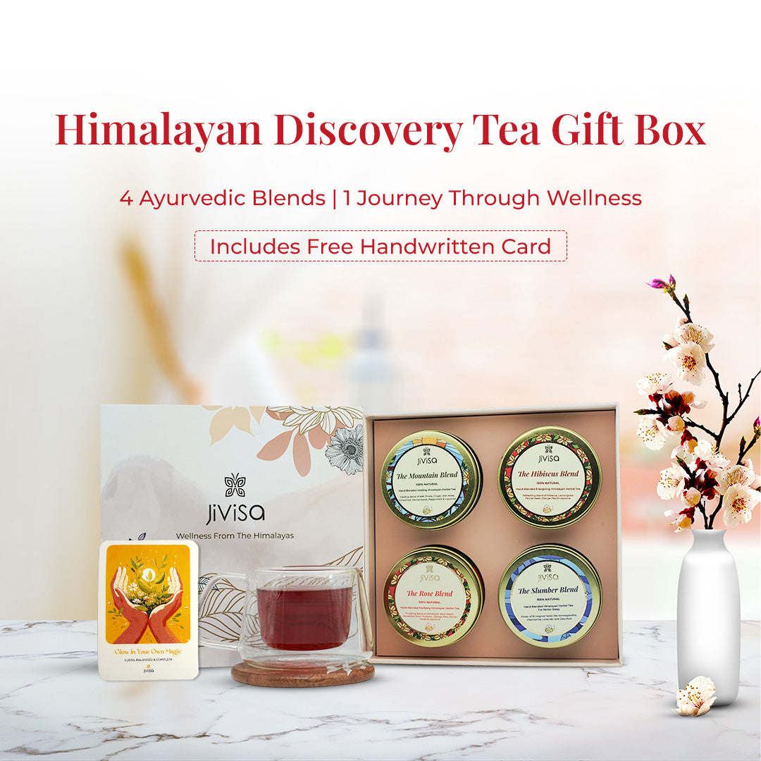 JiViSa Himalayan Discovery Tea Gift Box – 4 Ayurvedic Blends | 1 Journey Through Wellness. Includes Free Handwritten Card. The image shows Himalayan Discovery gift box set from JiViSa featuring four herbal tea tins- Mountain Blend, Hibiscus Blend, Rose Blend and Slumber Blend arranged neatly inside a pastel floral box. A clear glass cup of tea, a floral background, and a bright illustrated card reading “Glow In Your Own Magic” are placed beside it, reinforcing the wellness and gifting experience.