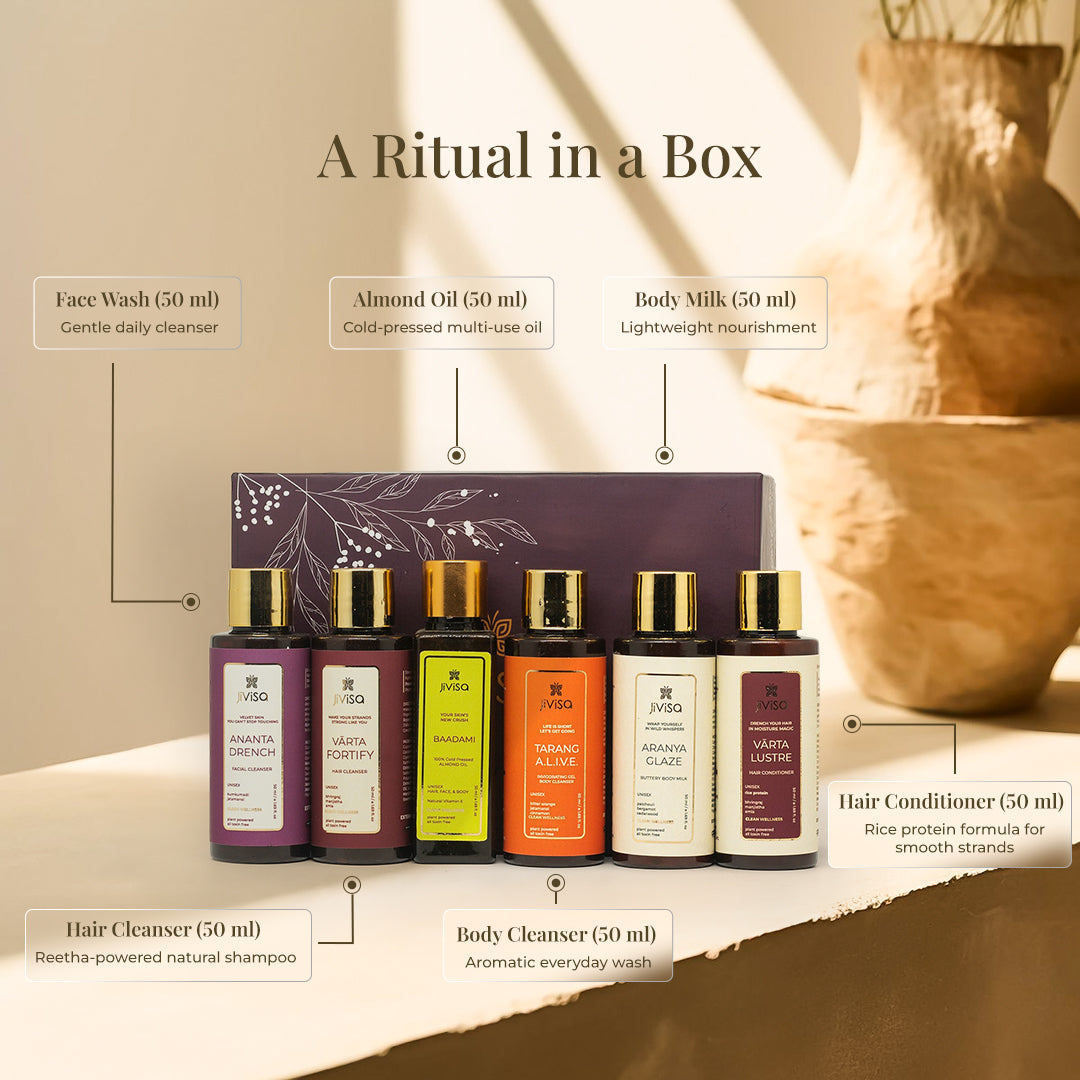 A detailed product shot of the JiViSa Soulful Self Care Gift Box, labeled with text pointers. Six colorful, 50ml bottles with gold caps are arranged. The labels identify the items as: Face Wash (Gentle daily cleanser), Hair Cleanser (Reetha-powered natural shampoo), Almond Oil (Cold-pressed multi-use oil), Body Cleanser (Aromatic everyday wash), Body Milk (Lightweight nourishment), and Hair Conditioner (Rice protein formula for smooth strands). The headline reads: "A Ritual in a Box".