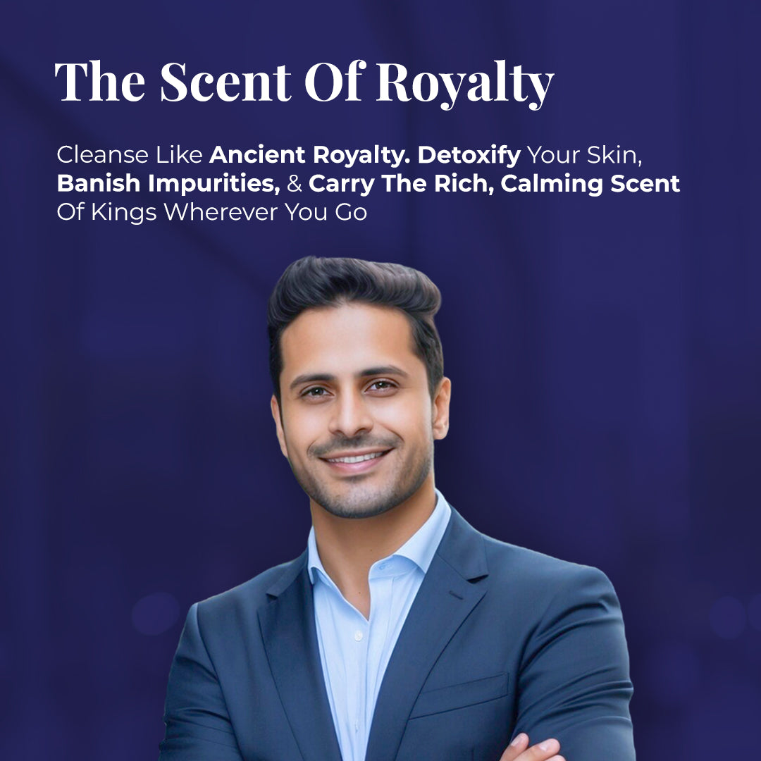 Smiling man in a dark blue suit and light blue shirt, looking directly at the viewer with arms crossed. Tagline: The Scent of Royalty. Text describes the benefits of JiViSa Arabic Oudh Ayurvedic Soap: Cleanse Like Ancient Royalty. Detoxify Your Skin, Banish Impurities, &amp; Carry the Rich, Calming Scent of Kings Wherever You Go.