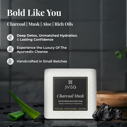 JiViSa Charcoal Musk Handcrafted Ayurvedic Soap bar placed on a dark textured surface with a piece of charcoal and an aloe vera leaf. Tagline: Bold Like You. Text lists key ingredients: Charcoal | Musk | Aloe | Rich Oils. Benefits listed: Deep Detox, Unmatched Hydration, &amp; Lasting Confidence, Experience the Luxury of The Ayurvedic Cleanse, Handcrafted in Small Batches.