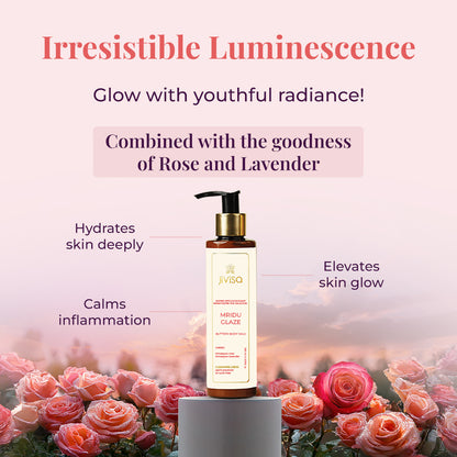 A JiViSa Mridu Glaze Buttery Body Milk bottle stands on a small pedestal, surrounded by lush pink and red roses with water droplets on their petals. Tagline reads &quot;Irresistible Luminescence&quot; followed by the text Glow with youthful radiance below the tagline. The text highlights product ingredients in a pastel color box: Combined with the goodness of Rose and Lavender. Callouts around the bottle indicate benefits: Hydrates skin deeply, Calms inflammation, and Elevates skin glow.