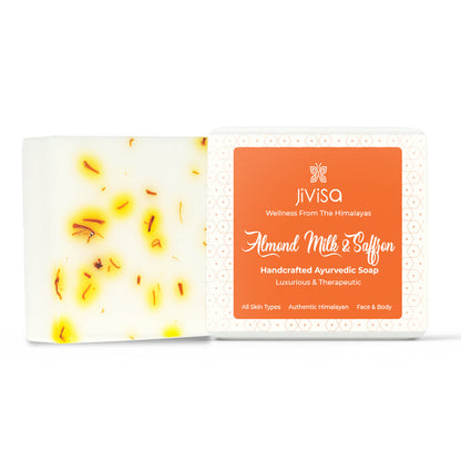 JiViSa Almond Milk &amp; Saffron Handcrafted Ayurvedic Soap with visible saffron strands in the soap bar and orange label packaging. The packaging highlights key USPs like “Luxurious &amp; Therapeutic,” “All Skin Types,” and “Authentic Himalayan.