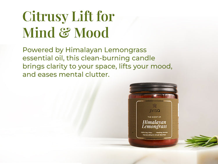 JiViSa Himalayan Lemongrass soy wax candle amber glass jar is positioned next to fresh lemongrass on a clean white surface with soft shadows and green foliage accents. The heading on the left reads: “Citrusy Lift for Mind & Mood.” Supporting text says: “Powered by Himalayan Lemongrass essential oil, this clean-burning candle brings clarity to your space, lifts your mood, and eases mental clutter.”