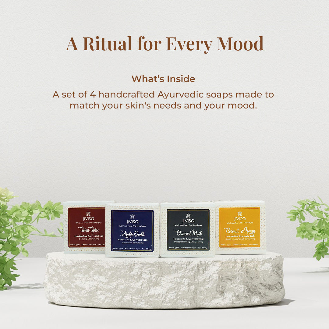 Tagline reads: &quot;A Ritual for Every Mood – A set of 4 handcrafted Ayurvedic soaps made to match your skin’s needs and your mood&quot; followed by a minimal stone pedestal display of the four soaps arranged in a row. Each soap stands distinct in color and label: Seven Spice (red), Arabic Oudh (deep blue), Charcoal Musk (black), and Coconut &amp; Honey (golden yellow), evoking a multi-sensory bathing ritual.