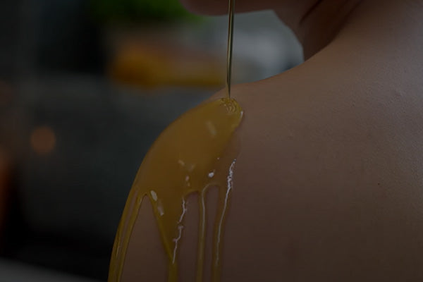 Close-up of oil being poured onto skin.