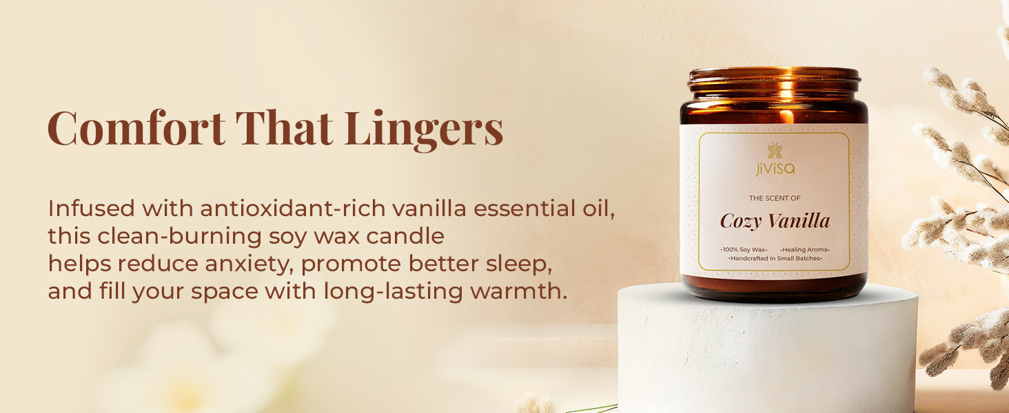 JiViSa Cozy Vanilla soy wax candle glass jar is displayed on a light pedestal against a beige, softly-lit backdrop with dried foliage accents, creating a warm and calming atmosphere. The tagline reads: "Comfort That Lingers," followed by the text: "Infused with antioxidant-rich vanilla essential oil, this clean-burning soy wax candle helps reduce anxiety, promote better sleep, and fill your space with long-lasting warmth."