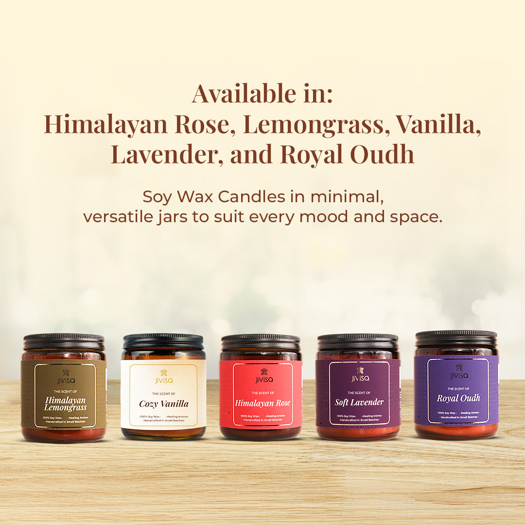 A lineup of five JiViSa soy wax candles is displayed on a wooden surface. Text above reads: &quot;Available in: Himalayan Rose, Lemongrass, Vanilla, Lavender, and Royal Oudh,&quot; followed by text: &quot;Soy Wax Candles in minimal, versatile jars to suit every mood and space.&quot;