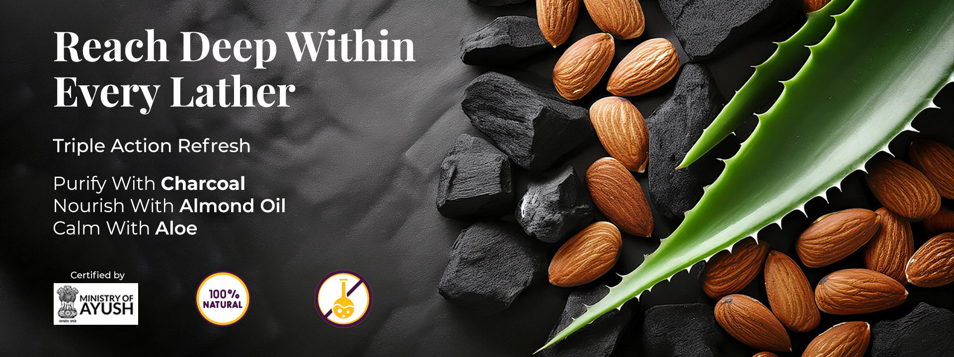 Dark background with JiViSa Charcoal Musk Ayurvedic Handmade Soap natural ingredients: chunks of charcoal, aloe vera, and almonds. The heading reads: “Reach Deep Within Every Lather.” Subtext: 'Triple Action Refresh.' Three callouts follow: Purify With Charcoal, Nourish With Almond Oil, Calm With Aloe. Certification icons at the bottom: Ministry of AYUSH, 100% Natural, and Herbal Science. Together, the visuals and text reflect a fulfilling cleanse—deep, gentle, and soothing.