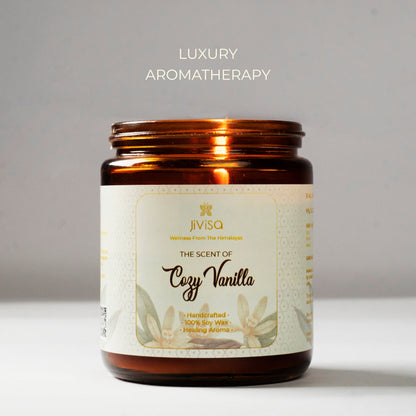 JiViSa Cozy Vanilla soy wax candle in a glossy amber glass jar against a clean grey background. The candle label reads: &quot;JiViSa – Wellness From The Himalayas – The Scent of Cozy Vanilla – Handcrafted • 100% Soy Wax • Healing Aroma.&quot; Above the jar, the text &quot;Luxury Aromatherapy&quot; is displayed, emphasizing the premium sensory experience.