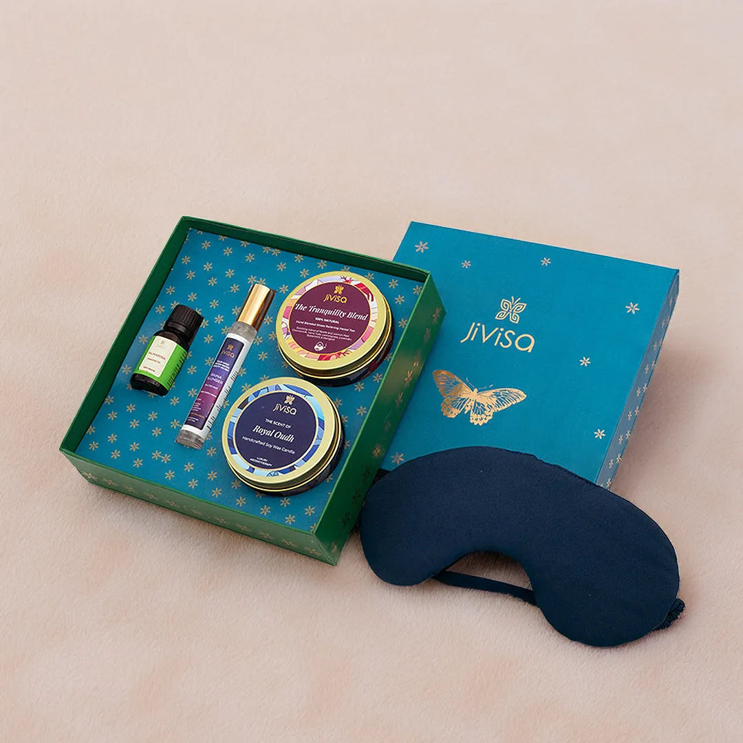 JiViSa Dreamscape Relaxation Gift Set open box featuring Royal Oudh candle, Tranquility Blend tea, Raina Slumber pillow mist, Palmarosa oil, and navy silk sleep mask