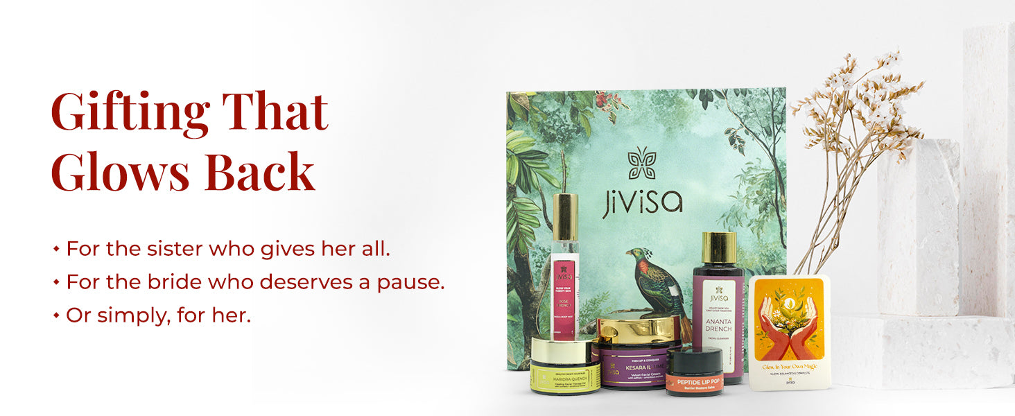 JiViSa Himalayan Glow Ritual For Her Gift Box displayed with its skincare products—Ananta Drench Cleanser, Rose Drench Mist, Kesara Illume Cream, Haridra Quench Gel, and Peptide Lip Pop—paired with a gift card arranged beside dried white flowers on a white textured background. The nature-inspired green gift box features a bird and foliage design. Text on the left reads: “Gifting That Glows Back.” Subtext: “For the sister who gives her all | For the bride who deserves a pause | Or simply, for her.”


