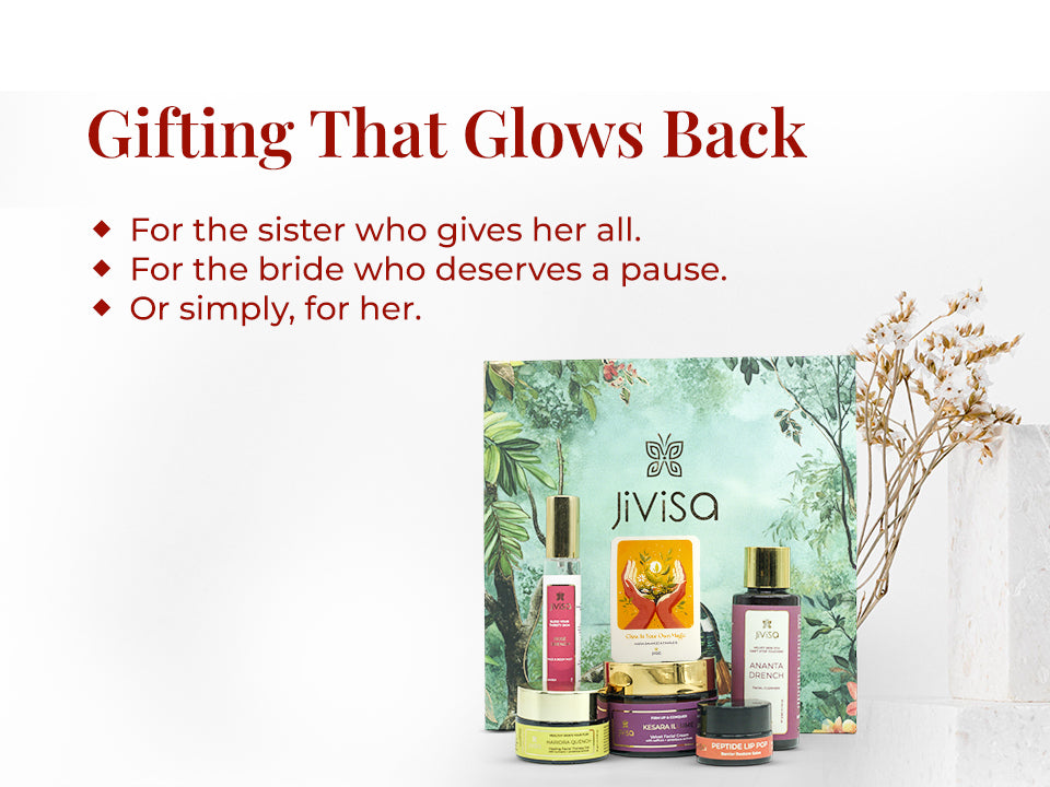 JiViSa Himalayan Glow Ritual For Her Gift Box displayed with its skincare products—Ananta Drench Cleanser, Rose Drench Mist, Kesara Illume Cream, Haridra Quench Gel, and Peptide Lip Pop—paired with a gift card arranged beside dried white flowers on a white textured background. The nature-inspired green gift box features a bird and foliage design. Text on the left reads: “Gifting That Glows Back.” Subtext: “For the sister who gives her all | For the bride who deserves a pause | Or simply, for her.”
