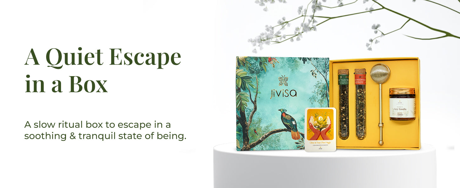 JiViSa Brew & Bliss Aroma Gift Set open to reveal two JiViSa herbal tea blends in glass tubes, a brass tea infuser, Cozy Vanilla aromatherapy candle, and a glow affirmation card, placed beside its nature-inspired green gift box with bird and foliage design. Text on the left reads: “A Quiet Escape in a Box.” Subtext: A slow ritual box to escape in a soothing & tranquil state of being.