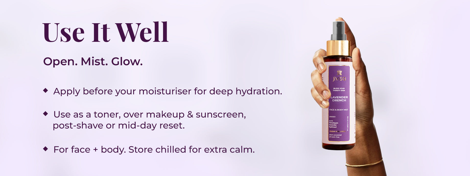 The image shows a hand holding JiViSa Lavender Drench Face & Body Mist on the right side, with usage instructions presented on the left. The heading reads Use It Well followed by the tagline "Open. Mist. Glow." Below, three points explain how to use the mist: apply it before moisturizer for deep hydration; use it as a toner, over makeup and sunscreen, post-shave, or as a mid-day reset; and it is suitable for both face and body, with a suggestion to store it chilled for extra calm.