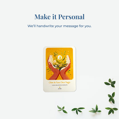 &quot;Make it personal – We’ll handwrite your message for you.&quot; A handwritten card with warm yellow and orange tones shows two hands holding blooming herbs with a glowing sun. Placed on a white surface, the image emphasizes the personal, heartfelt gifting experience JiViSa offers.