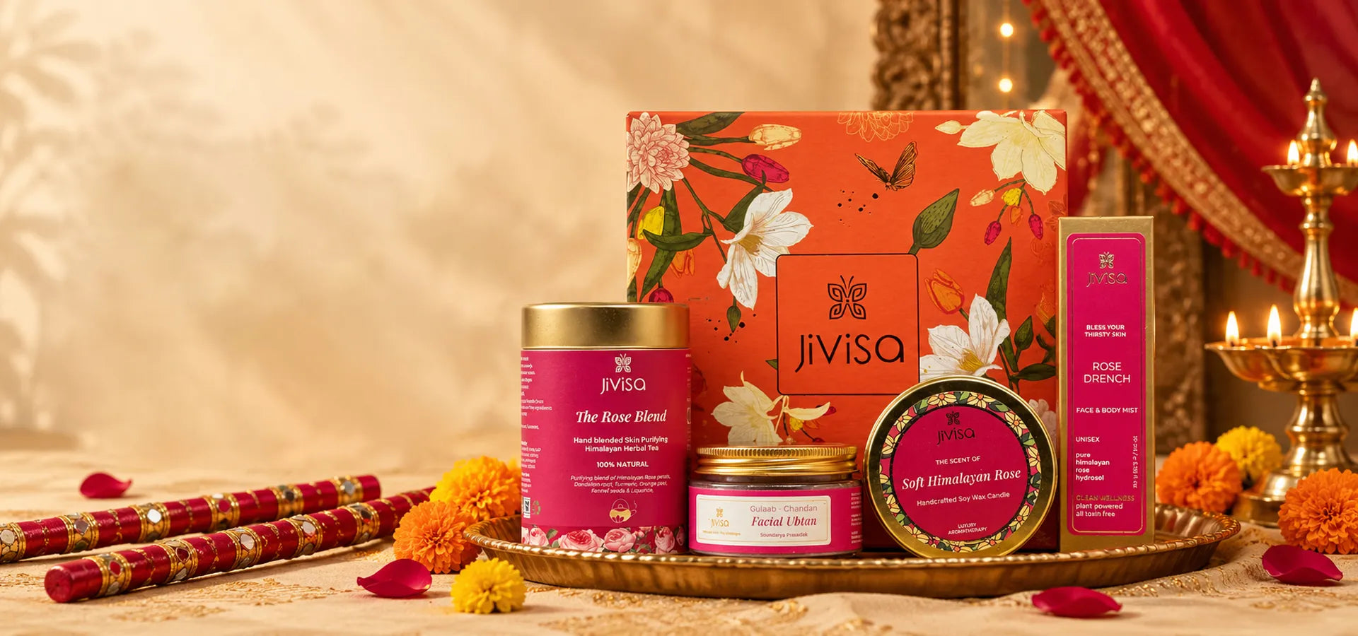 JiViSa Navratri gift set with Rose Blend tea, Facial Ubtan, Himalayan Rose candle, and Rose Drench mist, styled with dandiya sticks, marigolds, and diyas.