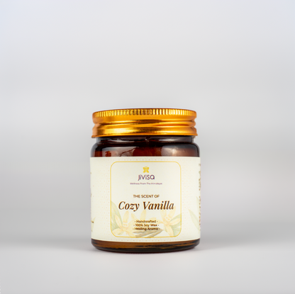 JiViSa Cozy Vanilla soy wax candle in a glossy amber glass jar with a golden lid, placed against a white background. The label reads: &quot;JiViSa – Wellness From The Himalayas – The Scent of Cozy Vanilla – Handcrafted • 100% Soy Wax • Healing Aroma.&quot;