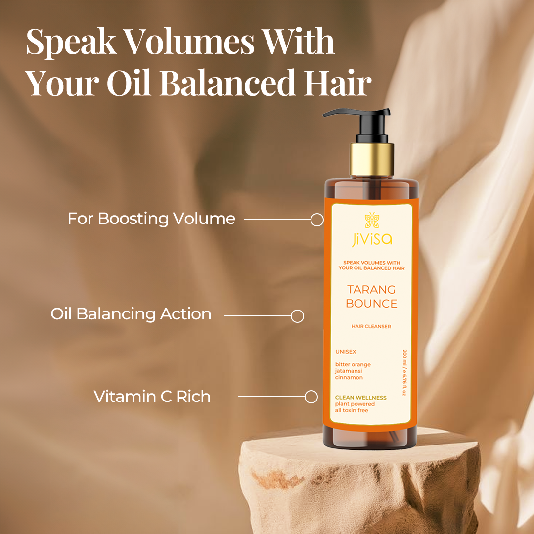 The image features a bottle of JiViSa Tarang Bounce Hair Cleanser placed on a stone platform with a soft beige fabric background. Text on the image reads "Speak Volumes With Your Oil Balanced Hair," highlighting the benefits of the product: "For Boosting Volume," "Oil Balancing Action," and "Vitamin C Rich." The bottle's label mentions key ingredients: bitter orange, jatamansi, and cinnamon, and highlights that the product is plant-powered and toxin-free.