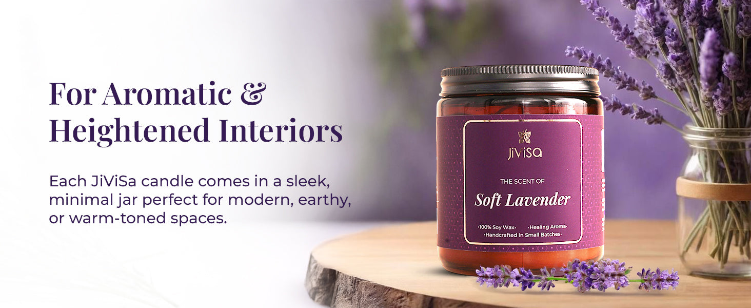 JiViSa Soft Lavender Soy Wax Candle placed on a wooden table with fresh lavender flowers and a lavender bouquet in the background. Tagline on top reads: “For Aromatic & Heightened Interiors.” Text below says: “Each JiViSa candle comes in a sleek, minimal jar perfect for modern, earthy, or warm-toned spaces.” The candle label reads: “JiViSa – The Scent of Soft Lavender – 100% Soy Wax • Healing Aroma • Handcrafted in Small Batches.”