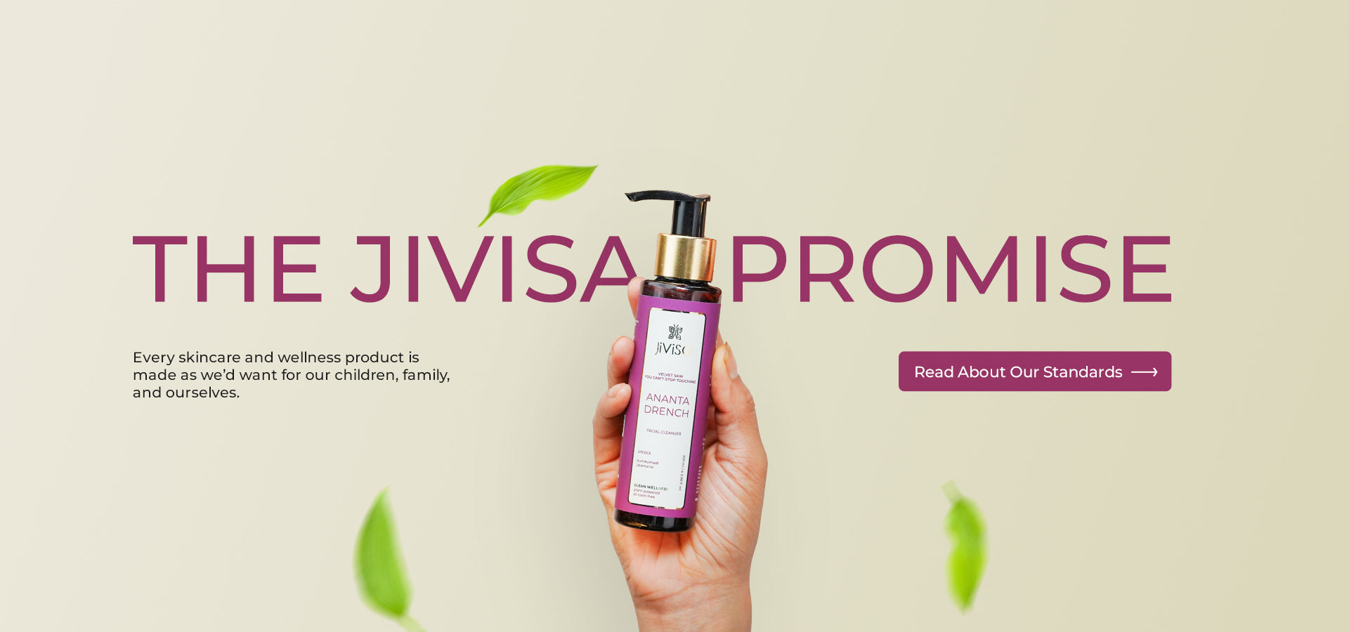 A hand holding JiViSa’s Ananta Drench Facial Cleanser bottle against a soft beige background with floating green leaves. The text reads “THE JIVISA PROMISE” with a subheading: “Every skincare and wellness product is made as we’d want for our children, family, and ourselves.” A button on the right says “Read About Our Standards."