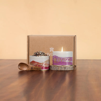 JiViSa herbal tea tin and lit soy candle with mountain-print labels displayed beside kraft gift box and wooden spoon on wood table