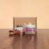 JiViSa herbal tea tin and lit soy candle with mountain-print labels displayed beside kraft gift box and wooden spoon on wood table