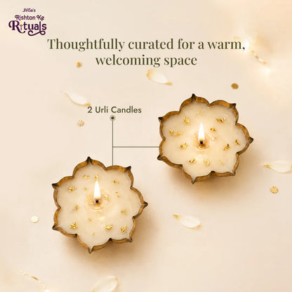 Two lit Urli Candles from the JiViSa Urli Elegance Aroma Box with gold leaf detail and soy wax, styled with petals