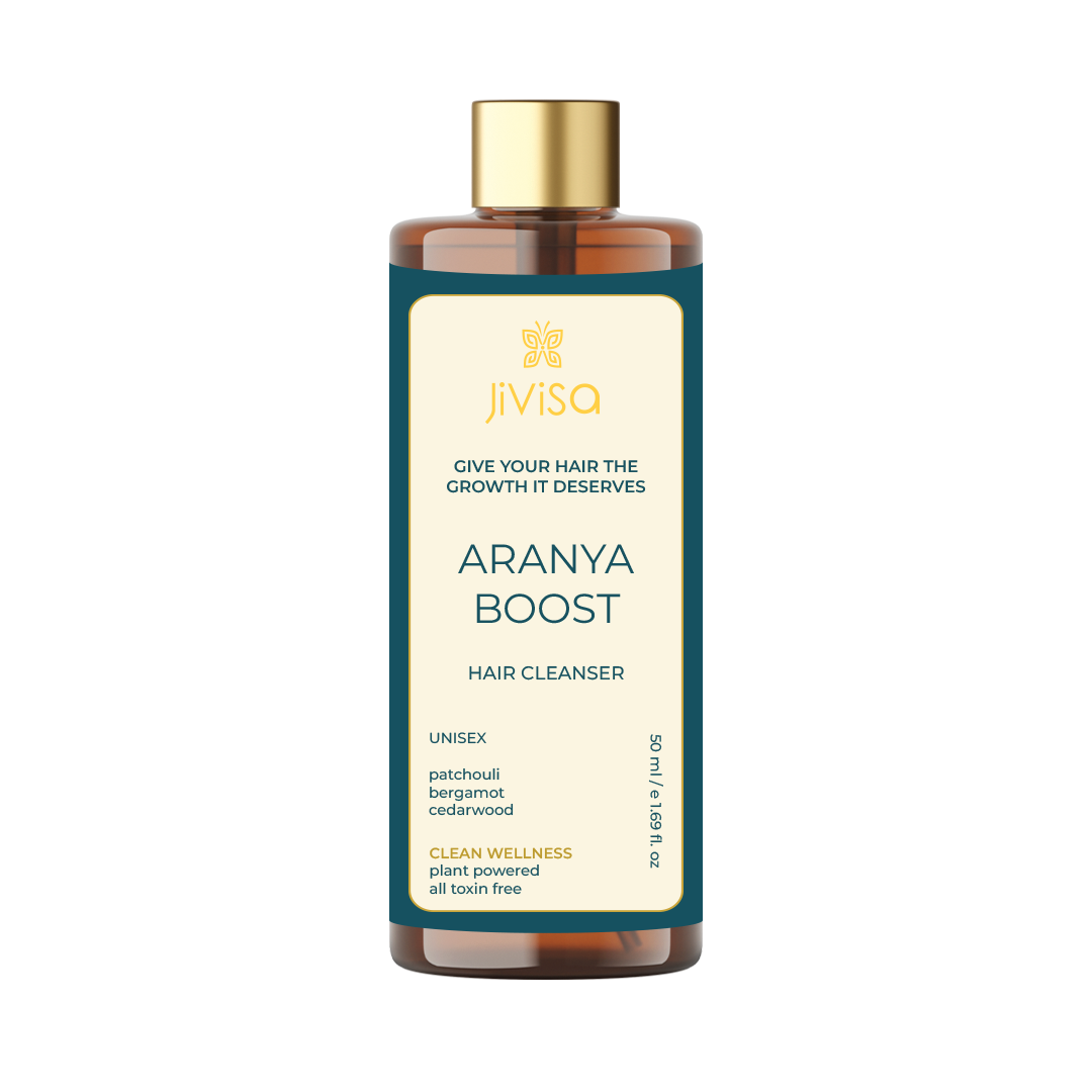 An amber bottle with a gold cap, labeled "JiViSa" and "GIVE YOUR HAIR THE GROWTH IT DESERVES." The product name "ARANYA BOOST HAIR CLEANSER" is prominently displayed, along with key ingredients: patchouli, bergamot, and cedarwood. It also mentions "CLEAN WELLNESS, plant powered, all toxin free.