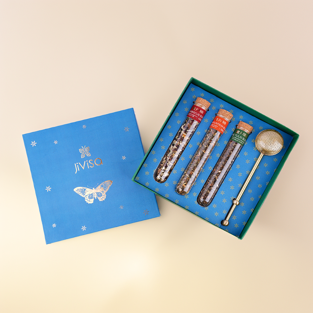 JiViSa Botanical Brew Tea Gift Box with three loose-leaf teas in glass test tubes and a premium brass infuser, in a luxury butterfly-illustrated blue box.