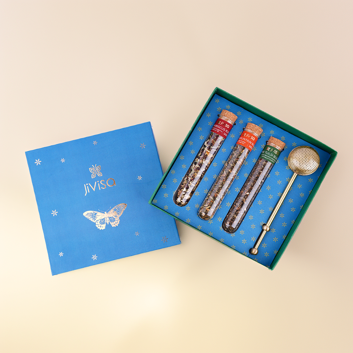JiViSa Botanical Brew Tea Gift Box with three loose-leaf teas in glass test tubes and a premium brass infuser, in a luxury butterfly-illustrated blue box.