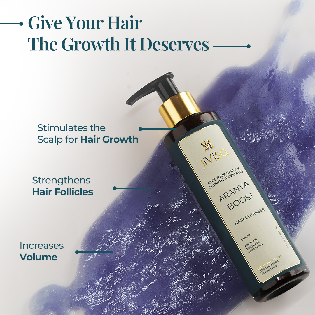 JiViSa Aranya Boost Hair Cleanser bottle with black pump cap on a background of purple liquid. Text overlay reads: 'Give Your Hair The Growth It Deserves'. Highlights benefits: Stimulates the scalp for hair growth, strengthens hair follicles, and increases hair volume.