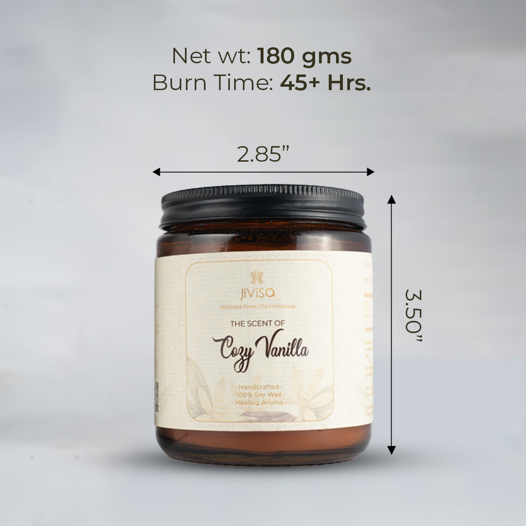  JiViSa Cozy Vanilla candle with a black lid, standing against a neutral grey background. Measurement indicators show the jar is 2.85 inches in diameter and 3.50 inches tall. Text on top reads: &quot;Net wt: 180 gms | Burn Time: 45+ Hrs.&quot; The label on the candle includes: &quot;Wellness From The Himalayas – The Scent of Cozy Vanilla – Handcrafted • 100% Soy Wax • Healing Aroma.&quot;