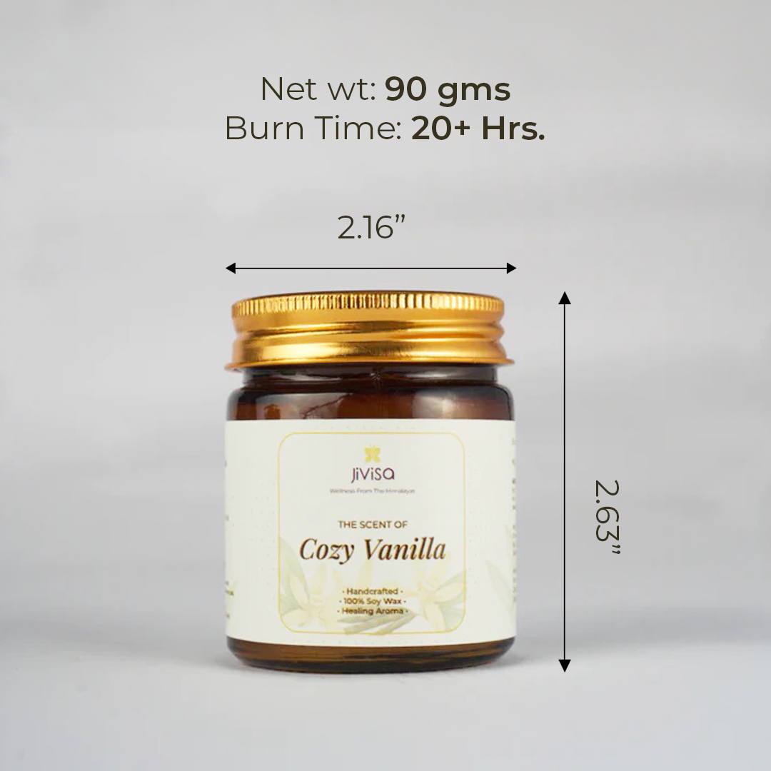 JiViSa Cozy Vanilla candle with a golden lid, standing against a neutral grey background. Measurement indicators show the jar is 2.16 inches in diameter and 2.63 inches tall. Text on top reads: &quot;Net wt: 90 gms | Burn Time: 20+ Hrs.&quot; The label on the candle includes: &quot;Wellness From The Himalayas – The Scent of Cozy Vanilla – Handcrafted • 100% Soy Wax • Healing Aroma.&quot;