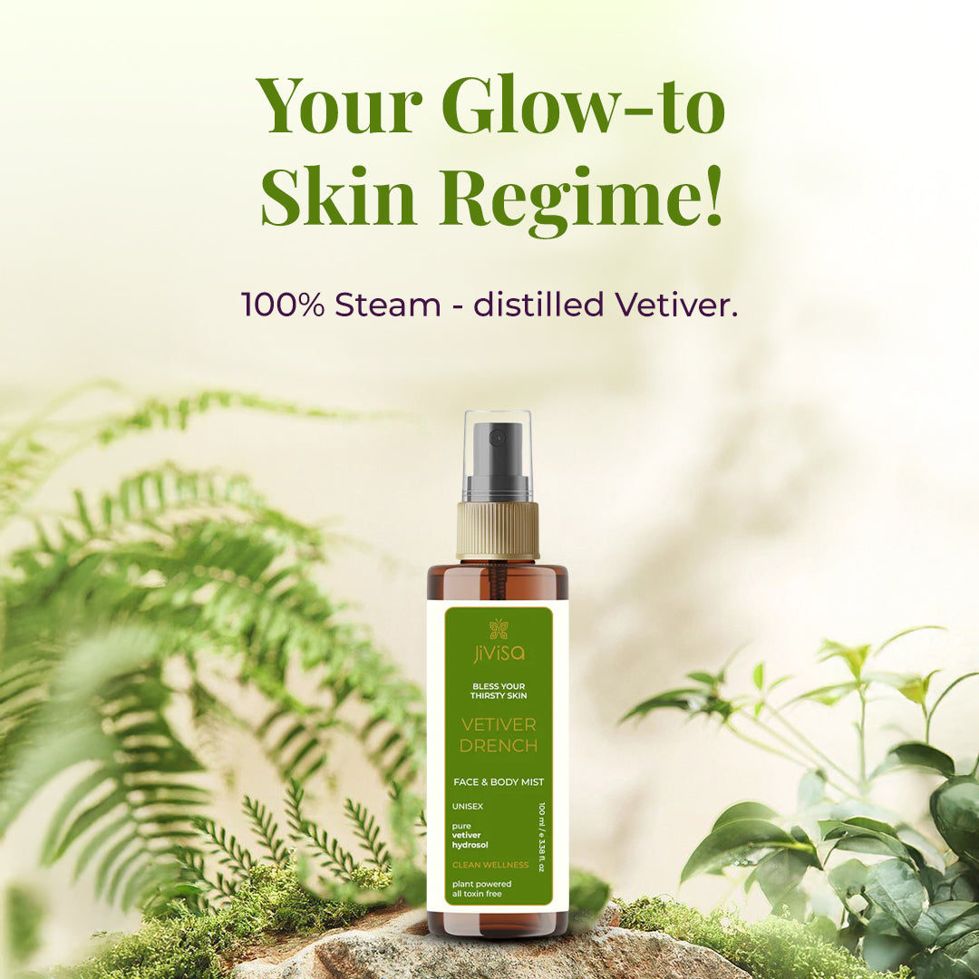 A bottle of JiViSa Vetiver Drench Face &amp; Body Mist is placed on a natural forest-like background with ferns and greenery. The label highlights it as a unisex, 100% steam-distilled vetiver hydrosol for clean, plant-powered all toxin free. The image features the text: &