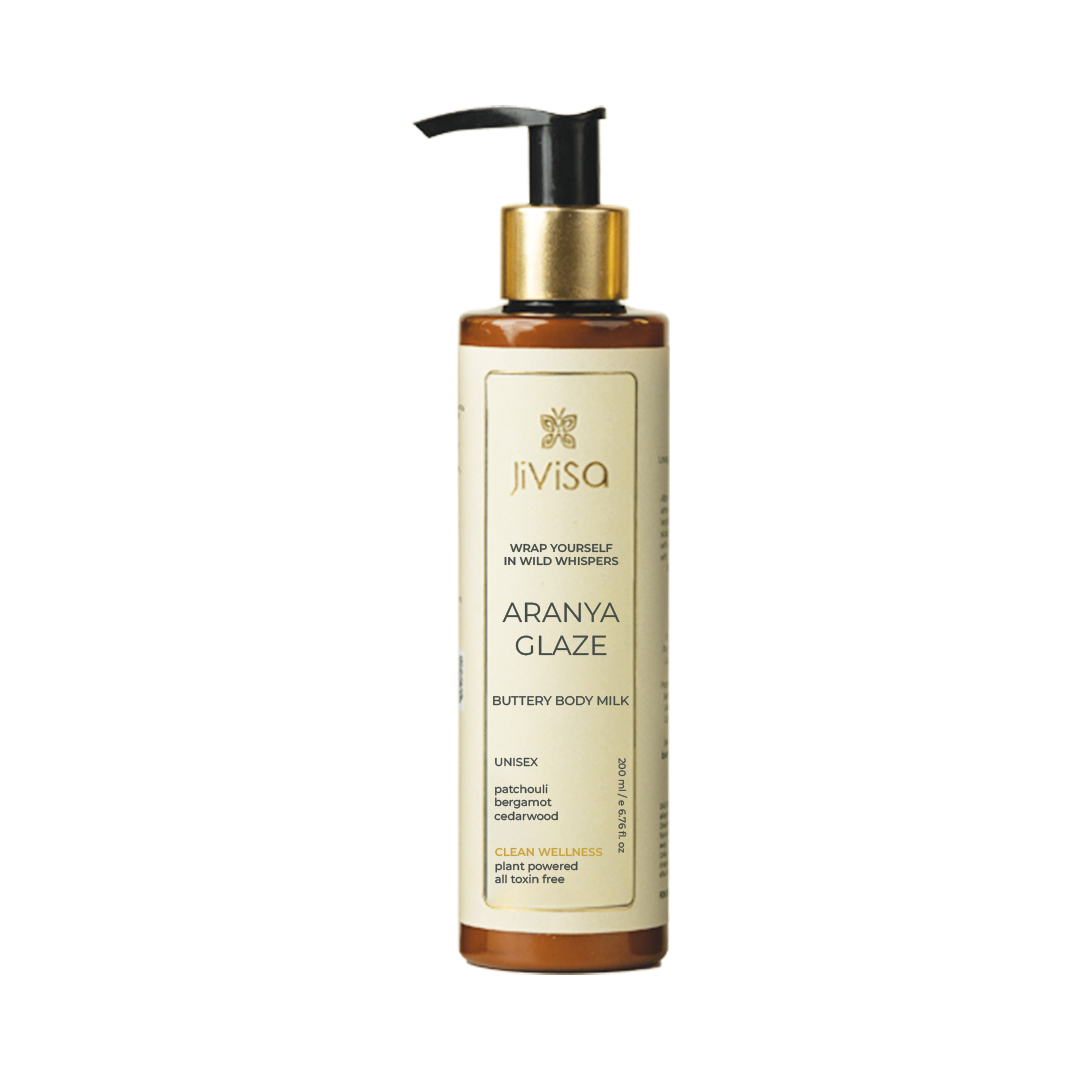 Front view of JiViSa Aranya Glaze Buttery Body Milk bottle with product name, key ingredients like patchouli, bergamot, cedarwood, and descriptions highlighting clean wellness and toxin-free formulation.